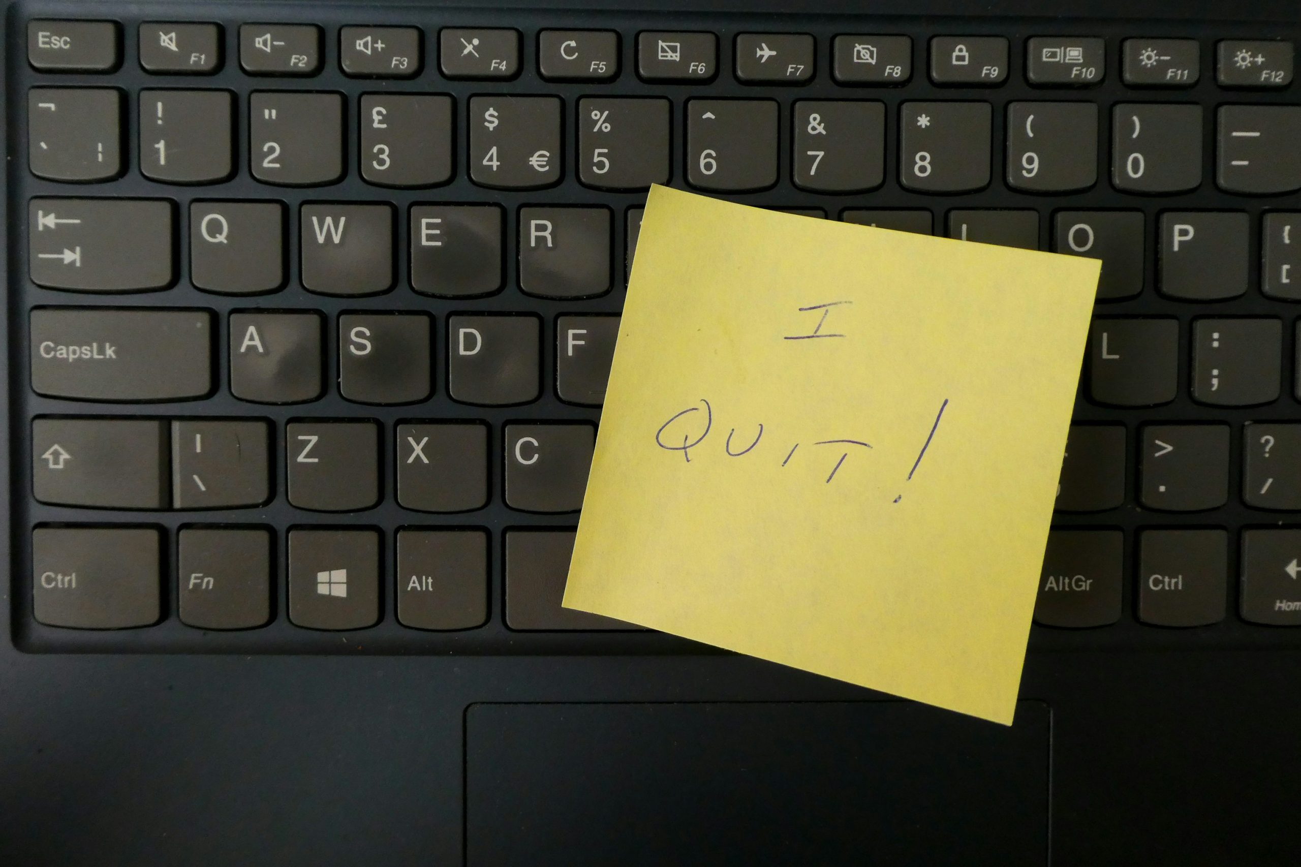 A yellow post-it note on a black keyboard, that says "I quit!"