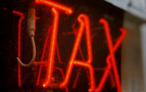 A read neon sign on a window that says "tax"